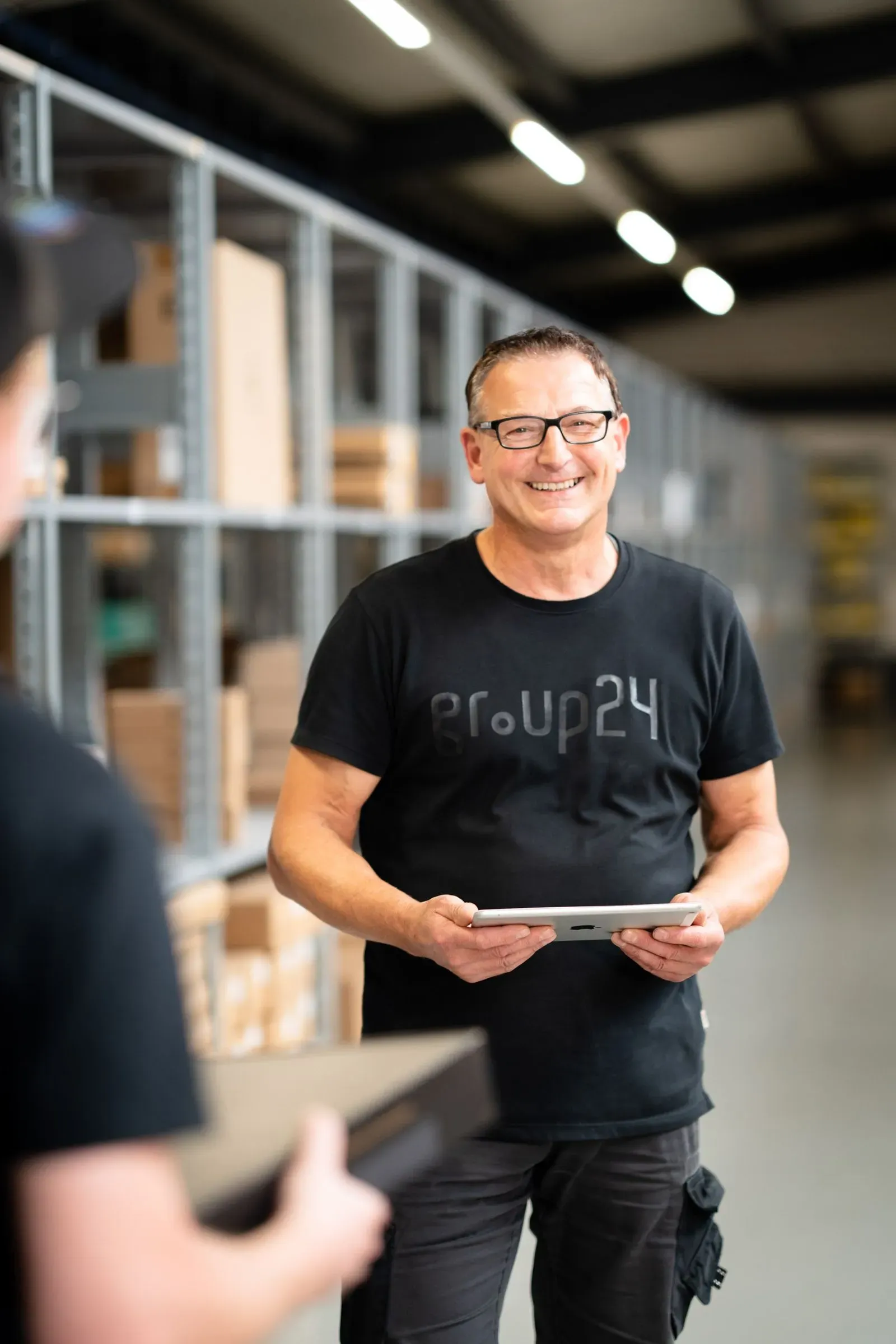 Mann mit Brille und Tablet in einer Werkhalle
